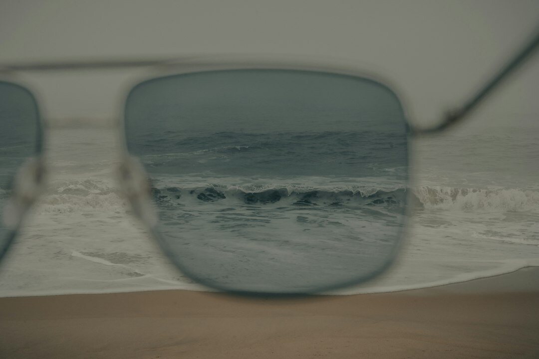 Pair of polarized luxury sunglasses resting on a weathered wooden table near the beach