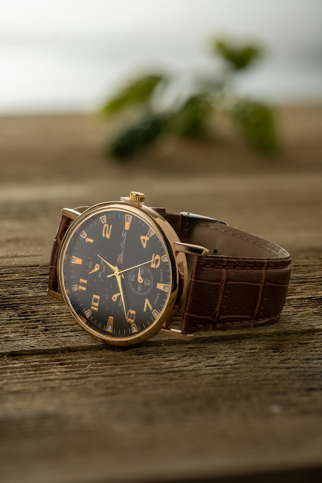 Studio product photograph of a slim gold dress watch with a leather strap